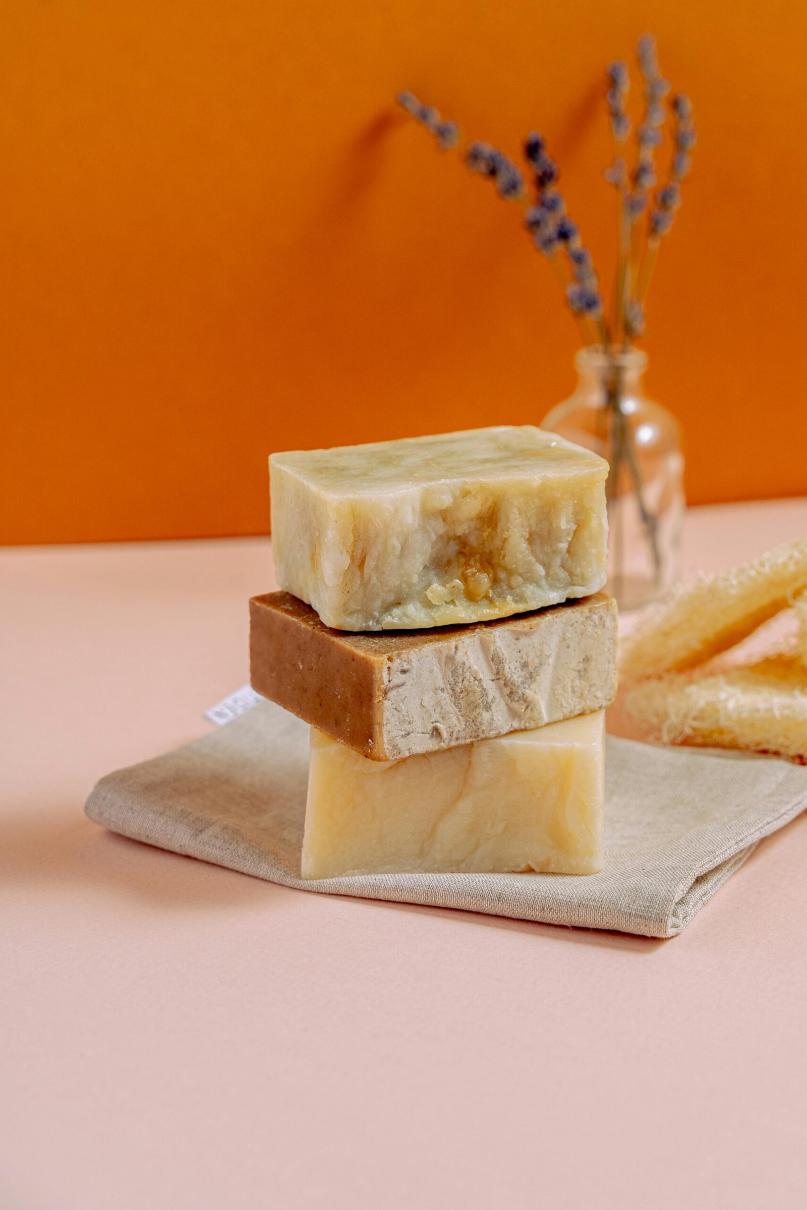 Three stacked natural handmade soap bars with lavender and honey on a pastel surface.